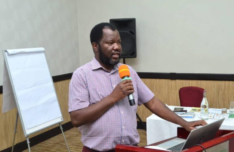 Benson Mukandiwa presenting beside a laptop and flip chart